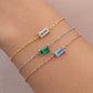 Three gold, silver, and rose gold bracelets with birthstones on a wrist.