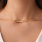 Gold name necklace with the name 'Claudia' worn by a female wearing a white top.