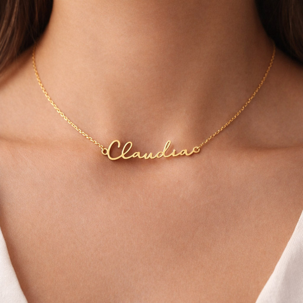 Gold name necklace with the name 'Claudia' worn by a female wearing a white top.
