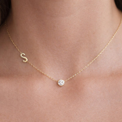 Gold necklace with personalised letter and small CZ birthstone worn by a female