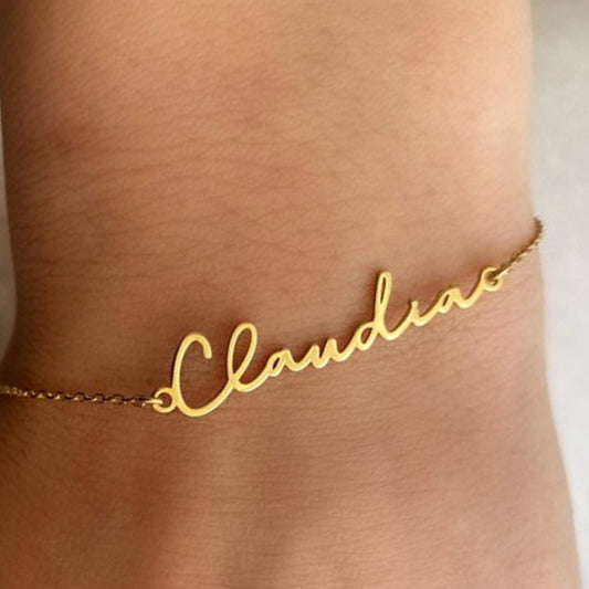 Gold name bracelet with the name 'Claudia' on a person's wrist